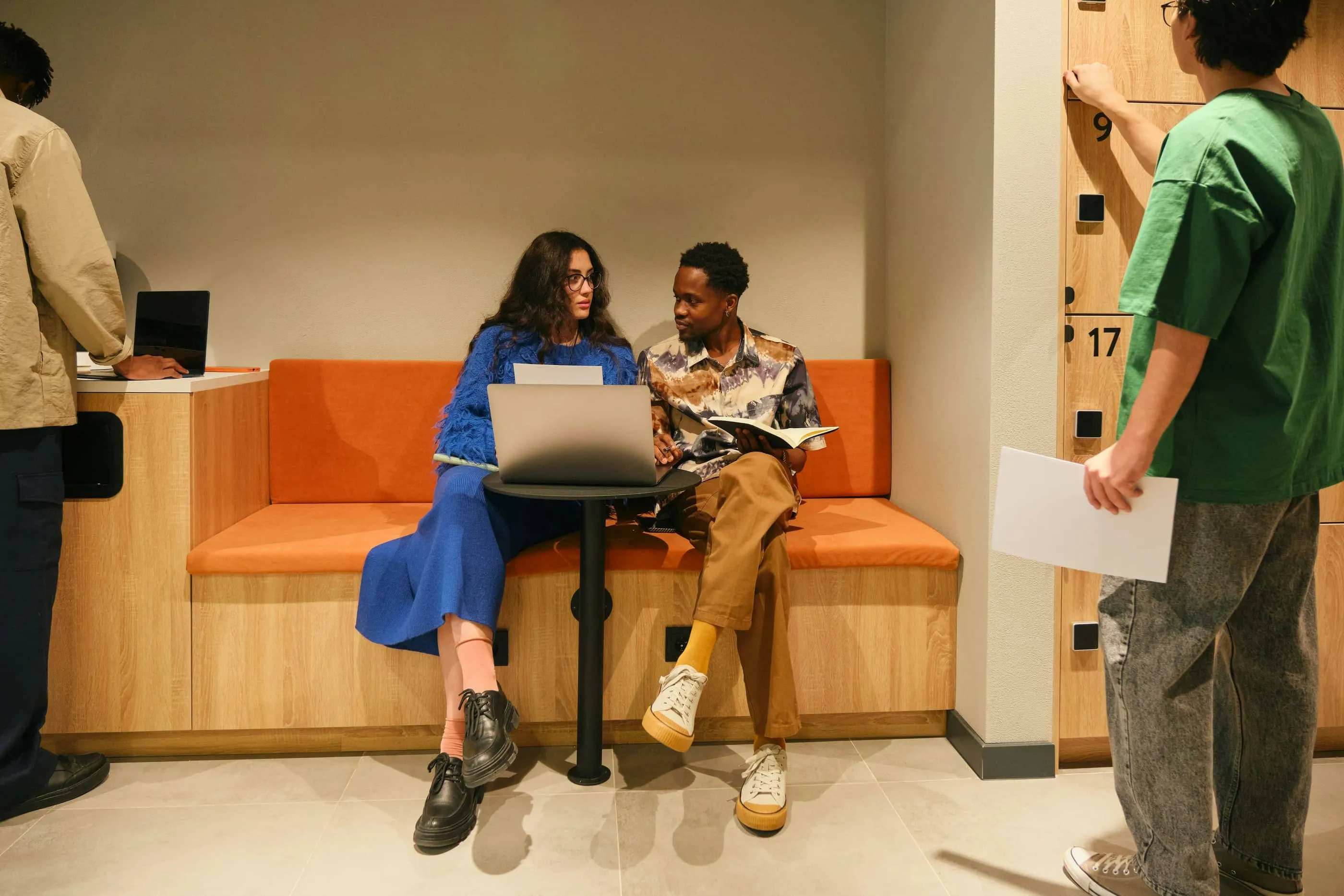 Two colleagues working together on a laptop in an office lounge